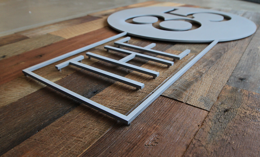 48" x 36" reclaimed wood panel with brushed aluminum logo assembled with spacers on face Installed with a cleat on the back of the panel to be flush to wall